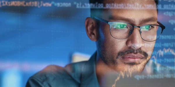 Man with glasses concentrating on code